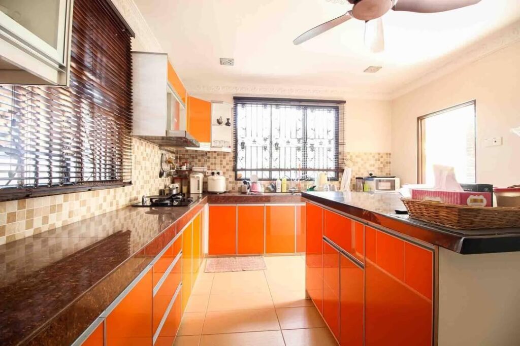 15. Glossy Warmth: High-Contrast Orange Cabinets with Brown Granite